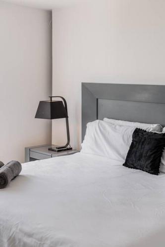 a white bed with a black pillow and a lamp at Seacost Beachfront 2BDR with pool by Casa Paraiso in Cancún