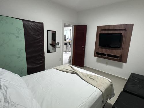 a bedroom with a bed and a flat screen tv at Casa Búzios - Temporada in Búzios