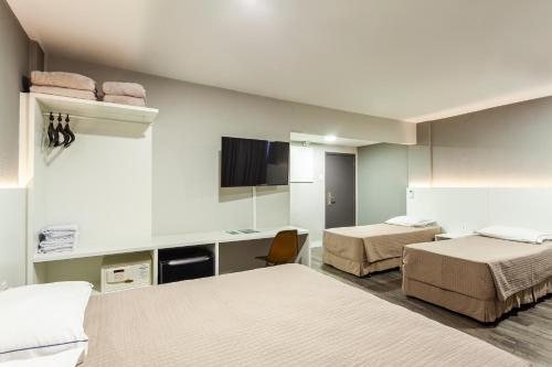 a hotel room with two beds and a tv at Marambaia Hotel e Convenções in Balneário Camboriú