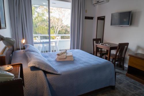 Habitación de hotel con cama, mesa y ventana en Apart Hotel Aguasol en Termas del Daymán