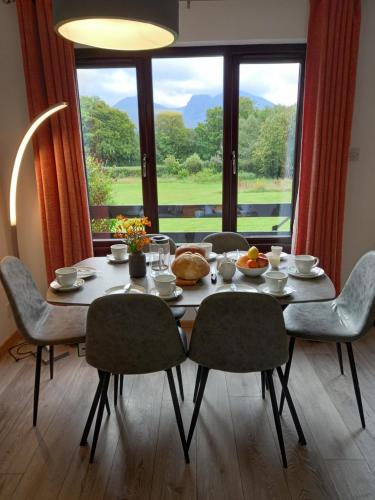 a dining room table with chairs and a large window at Hawthorn Lodge in Fort William