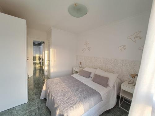 een witte slaapkamer met een bed en een raam bij El apartamento de MATITA - free parking and beach in Telde