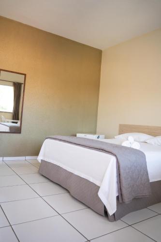 a hotel room with two beds and a mirror at Pousada Aeroporto in Parnaíba
