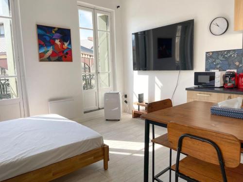 sypialnia z łóżkiem, biurkiem i telewizorem w obiekcie Vue sur la place des Halles, Art Apparts w Béziers