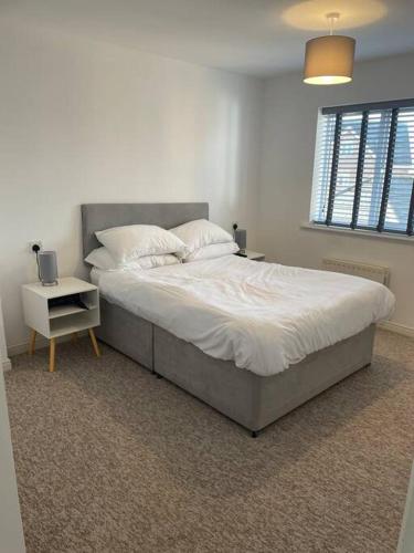 um quarto com uma cama grande com lençóis brancos e almofadas em 5 Holborn Spacious Home em Redhill