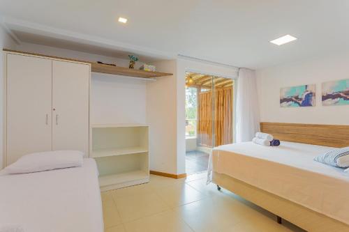 1 dormitorio blanco con 2 camas y ventana en IT01 Triplex 4 Suítes a 350m da Praia do Surf, en Camassari