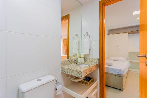 1 cama y baño con aseo y lavamanos. en IT01 Triplex 4 Suítes a 350m da Praia do Surf, en Camassari