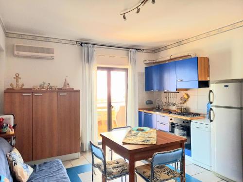 eine Küche mit einem Tisch und einem weißen Kühlschrank in der Unterkunft Blu Corallo in Mascali