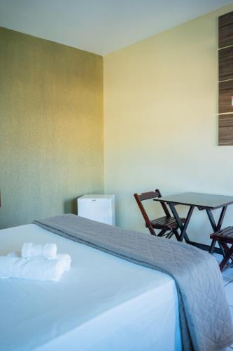 a bed in a room with a table and a table at Pousada Aeroporto in Parnaíba