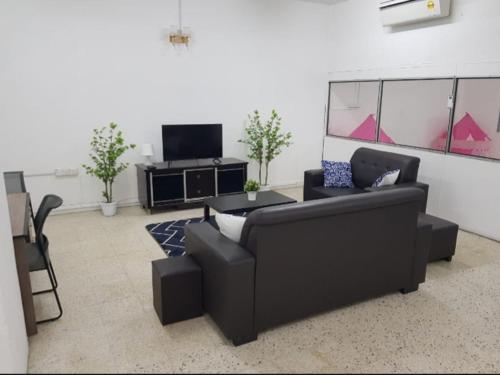 a living room with a black couch and a tv at Amilite Villa in Gelugor