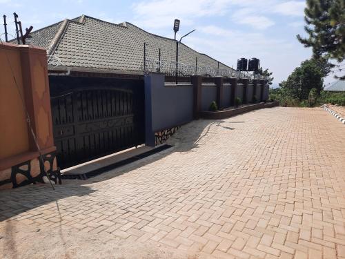 a brick driveway with a fence and a house at Deerwood Family Apartments, Bulenga in Bulenga