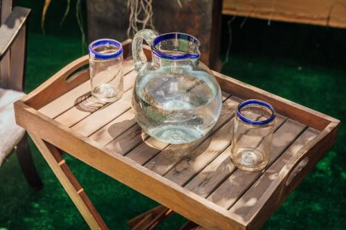 a glass jug and four glasses on a wooden tray at Maison du comte in Mexico City