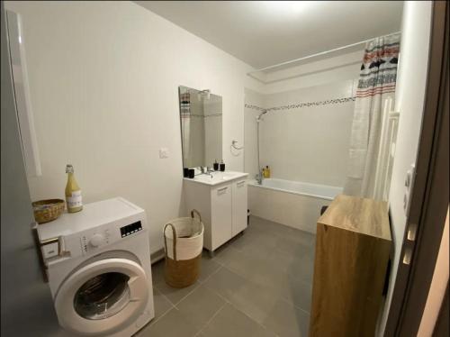 a bathroom with a washing machine and a bath tub at Appartement Stella-Plage in Cucq
