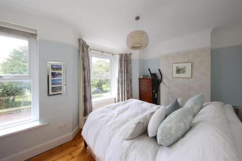 a bedroom with a white bed and two windows at Perfectly Positioned Pad in Cardiff