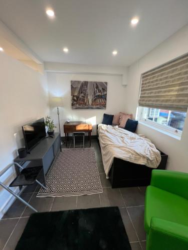 a bedroom with a bed and a desk and a couch at Modern flat in central Egham by Windsor Castle, Staines-Upon-Thames and Heathrow Airport in Egham