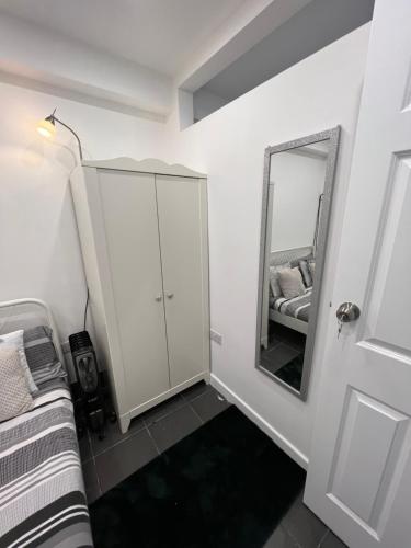 a bedroom with a white cabinet and a mirror at Modern flat in central Egham by Windsor Castle, Staines-Upon-Thames and Heathrow Airport in Egham