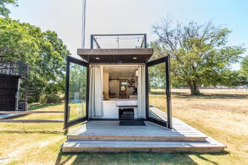 a small house with glass doors and a deck at The Honeycomb-Tiny Container Home 12 Min. to Magnolia/Baylor in Bellmead