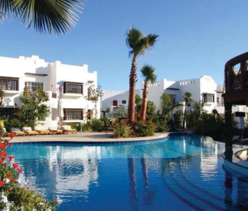 une grande piscine avec des palmiers et des bâtiments dans l'établissement Delta sharm resort. Studio. Sharm el sheikh, à Charm el-Cheikh