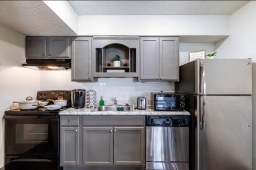 a kitchen with gray cabinets and a stainless steel refrigerator at The Cozy Clouds Resort at NRG in Houston