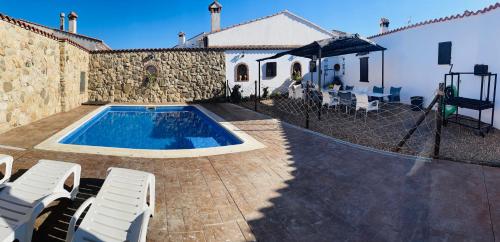 a swimming pool with two chairs and a house at Casa Rural Piedras de Benquerencia in Benquerencia