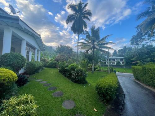 a house with a yard with palm trees and a driveway at Surveyor's Residence Bungalow in Kandy