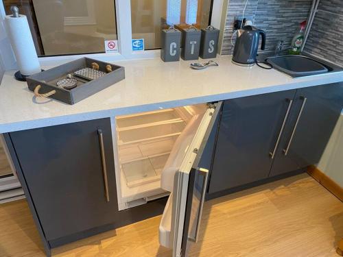a kitchen counter with an open refrigerator and a sink at Happy days Moreton , 2 miles from Hoylake Wirral in Moreton