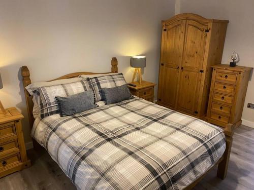 a bedroom with a bed with a plaid blanket and a cabinet at Happy days 2 miles from Hoylake Wirral in Moreton