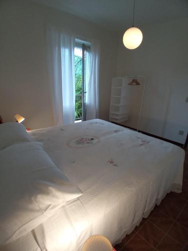 uma grande cama branca num quarto com uma janela em Ai Grilli - Ospitalità e natura em Casto