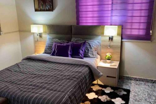 ein Schlafzimmer mit einem großen Bett mit lila Vorhängen in der Unterkunft Peniel Place in Makurdu