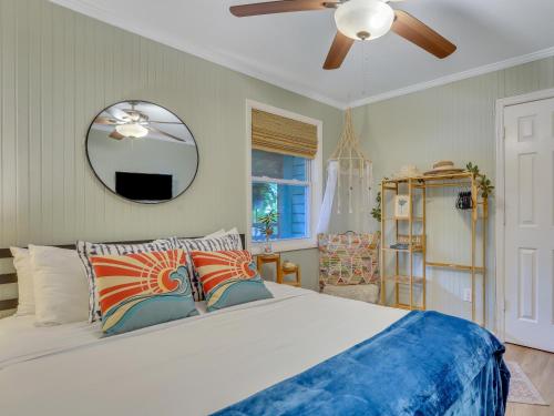 1 dormitorio con 1 cama con ventilador de techo y espejo en Salt Palms Cottage, en Tybee Island