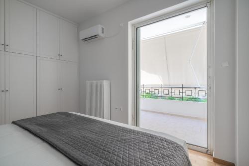 a bedroom with a bed and a large window at Varkiza Sea Front Residence in Vari