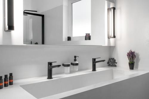 ein weißes Badezimmer mit Waschbecken und Spiegel in der Unterkunft Varkiza Sea Front Residence in Vari