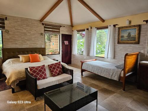 a bedroom with a bed and a couch and a table at Finca Paraiso Mountain Retreat near San Jose Airport in Birrí