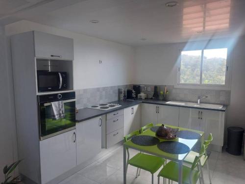 a kitchen with a table and green chairs in it at Citronnelles in Case-Pilote