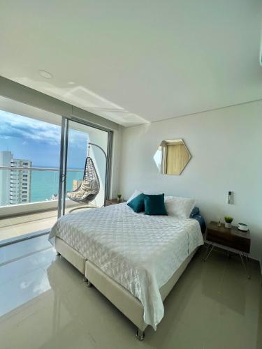 ein weißes Schlafzimmer mit einem Bett und einem großen Fenster in der Unterkunft Apartamento Moderno y lujoso con vista al mar Piso 1903 - cerca a ciudad amurallada in Cartagena de Indias