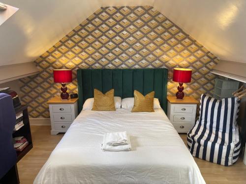 een slaapkamer met een bed met een groen hoofdeinde en 2 lampen bij Walpole House in Londen