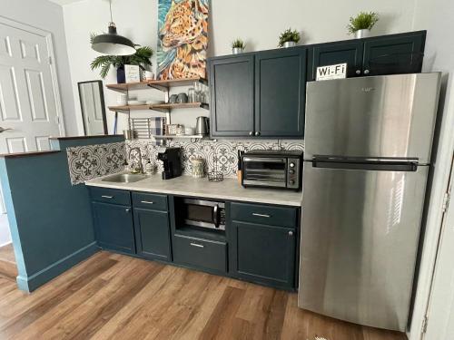 uma cozinha com armários azuis e um frigorífico de aço inoxidável em The Lafayette 'Tiny Home' Apartment em Lafayette