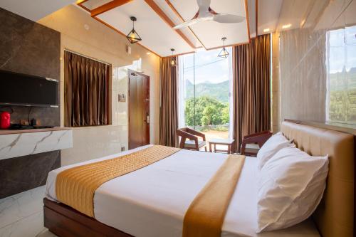 a hotel room with a bed and a large window at Zamin Resort in Kuttālam