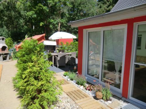 a garden with a red house and some plants at Ferienhaus Zingst MinHus in Zingst