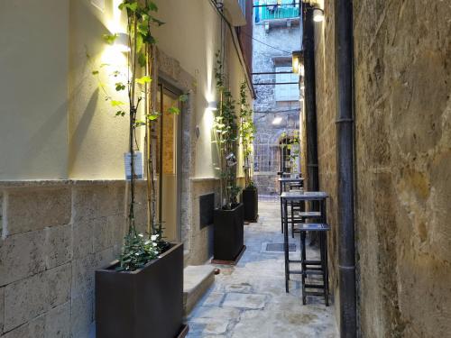 an alleyway with a row of stools and potted plants at DIONISO Bed & Wellness in Taranto