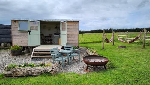a small cabin with a grill and a table and chairs at Shepherds Delight in Launceston