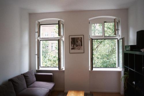 a living room with two windows and a couch at Room in the center of Berlin in Berlin