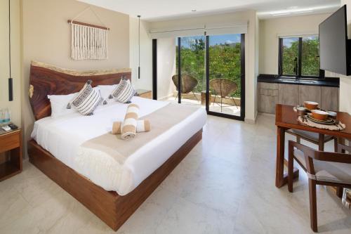 a bedroom with a large white bed and a desk at Cacao Tulum departamentos in Tulum