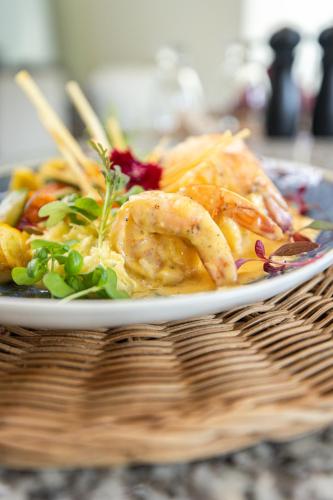 a plate of food with shrimp and vegetables on a table at Paradise Bay Hotel Boutique in Herradura