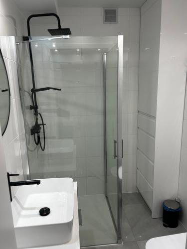 a white bathroom with a shower and a sink at APARTAMENT OFELIA in Darłowo