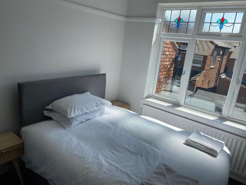 Una cama blanca en un dormitorio con ventana. en Sandringham House, en Redcar
