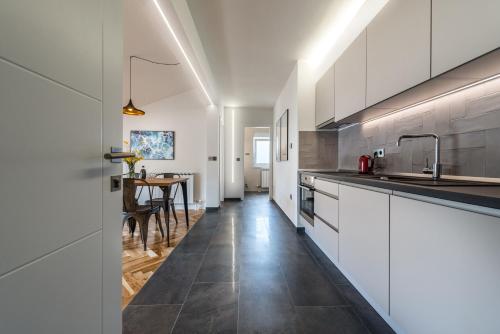 a kitchen with white cabinets and a dining table at The Park Apartment in Zadar