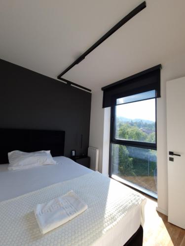 a bedroom with a white bed with a large window at Smart Loft Apartment in Tuzla