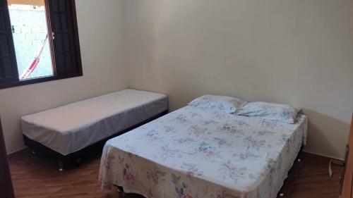 a bedroom with two beds and a window at Lar doce lar em Paraty in Paraty