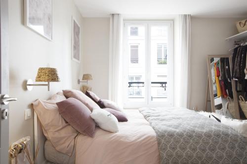 - une chambre avec un lit doté d'oreillers et d'une fenêtre dans l'établissement Appartement d'architecte - Puteaux Centre, à Puteaux